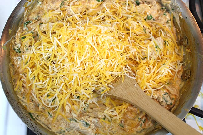 Adding shredded Cheese to the enchilada filling on the stove